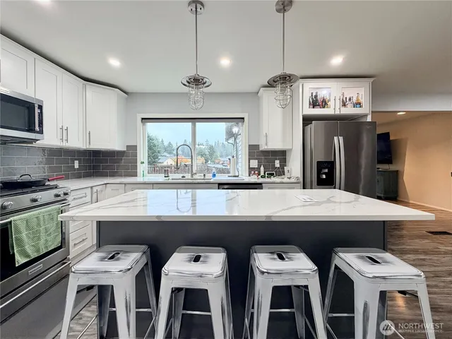 a kitchen with a dining table chairs stainless steel appliances and cabinets