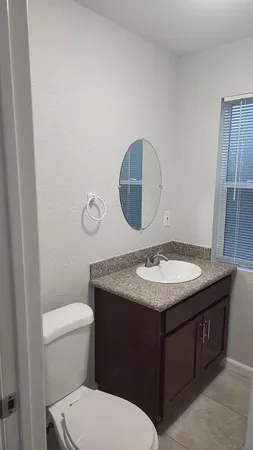 a bathroom with a granite countertop toilet sink and mirror