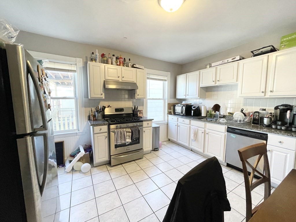 a kitchen with granite countertop a refrigerator stove top oven and sink