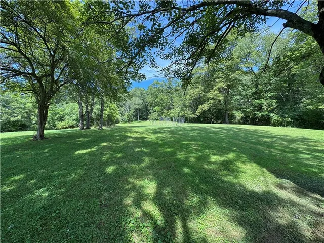a view of grassy field with benches and trees all around