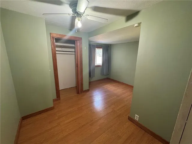 an empty room with wooden floor and fan