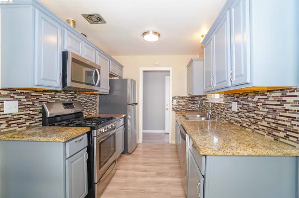 a kitchen with stainless steel appliances granite countertop a stove a sink and a microwave