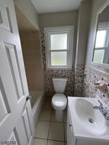 a bathroom with a sink toilet a window and tub