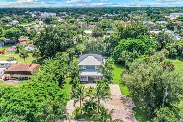 an aerial view of a house with a yard and large tree