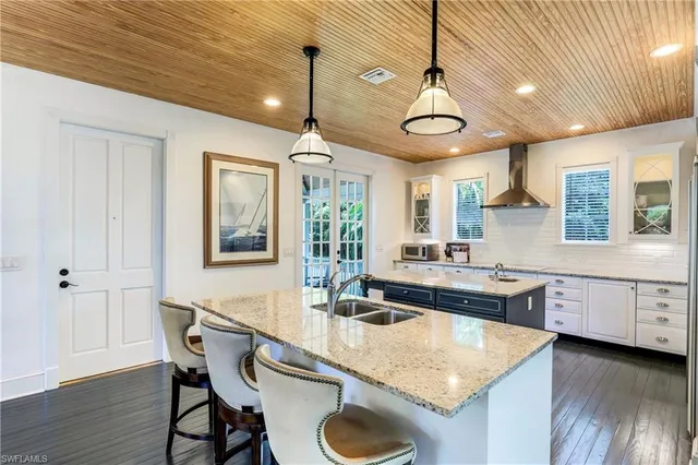 a kitchen with stainless steel appliances granite countertop a sink a stove and chairs with wooden floor