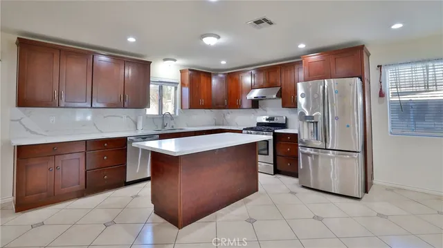 a kitchen with kitchen island granite countertop wooden cabinets and refrigerator