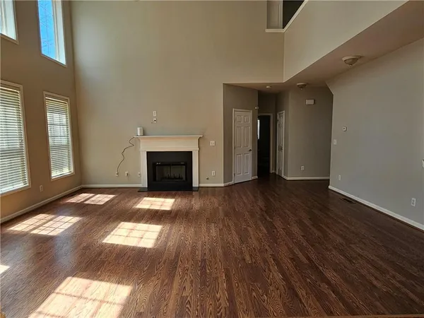 an empty room with wooden floor fireplace and windows