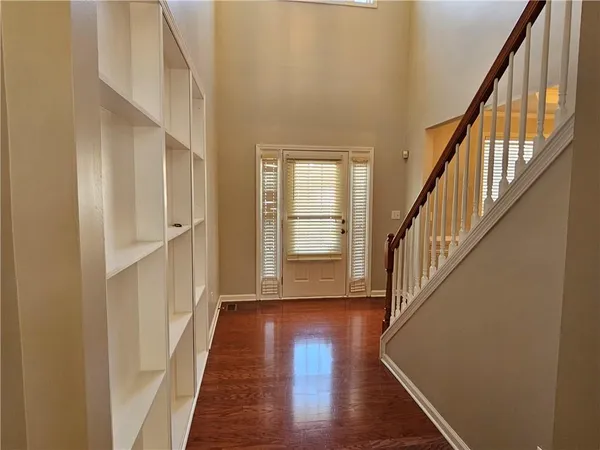 a view of an empty room with wooden floor and a kitchen