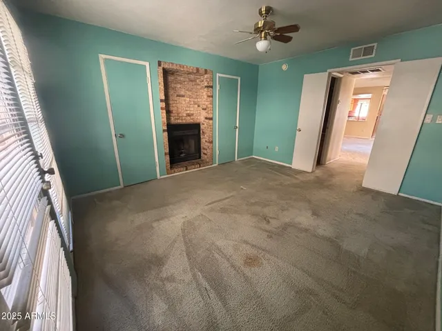 a view of an empty room with a fireplace and a window