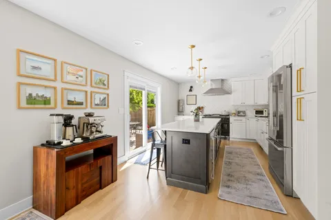 a kitchen with stainless steel appliances granite countertop a stove top oven a sink dishwasher a dining table and chairs with wooden floor
