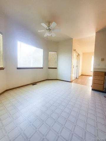 an empty room with windows and chandelier fan