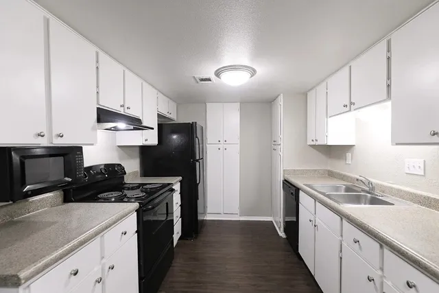 a kitchen with a sink dishwasher a stove and a refrigerator with wooden cabinets