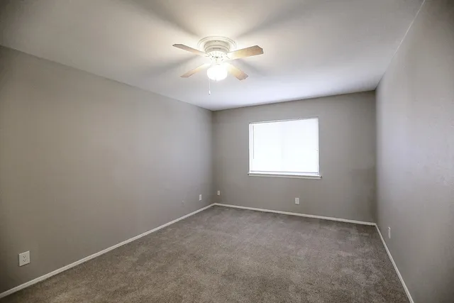 an empty room with a window and a fan
