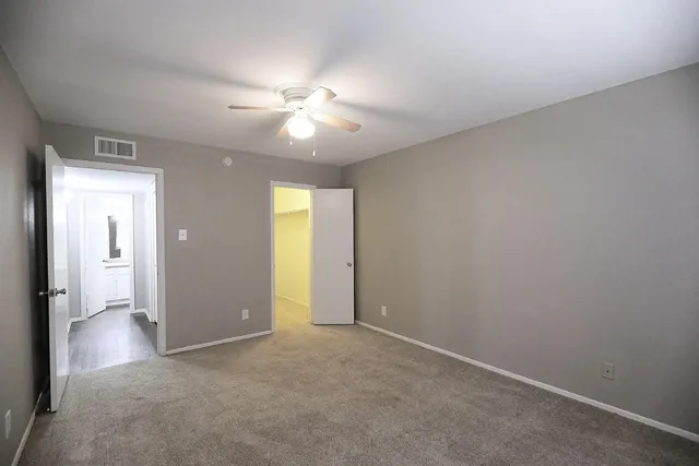 an empty room with closet and a chandelier fan