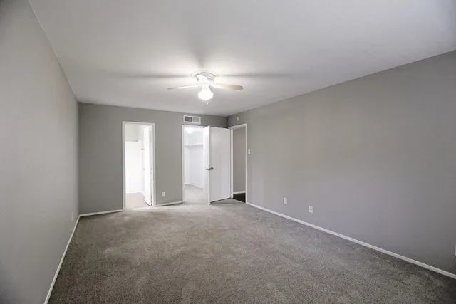 a view of an empty room with a chandelier fan