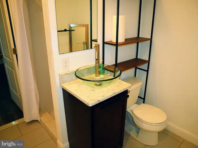 a bathroom with a granite countertop sink toilet and a mirror