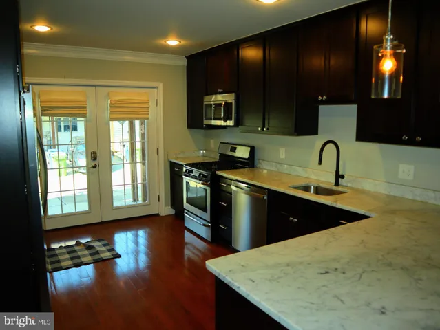 a kitchen with stainless steel appliances granite countertop a sink a stove and a wooden cabinets
