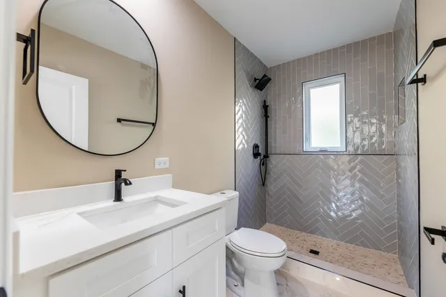 a bathroom with a sink a mirror a toilet and shower