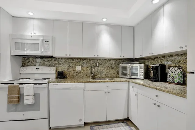 a kitchen with granite countertop white cabinets and white appliances