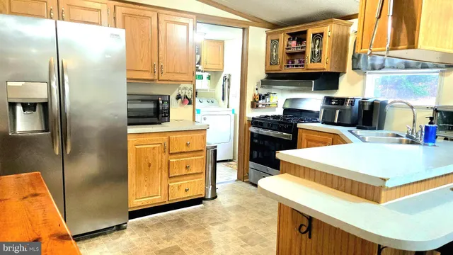 a kitchen with stainless steel appliances granite countertop a refrigerator a stove and a sink with large cabinets