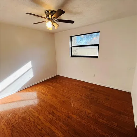 a view of an empty room with a window and wooden floor