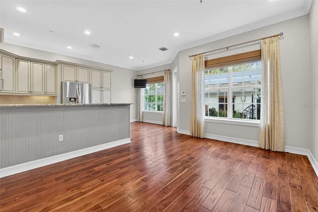a view of an empty room with wooden floor and a window
