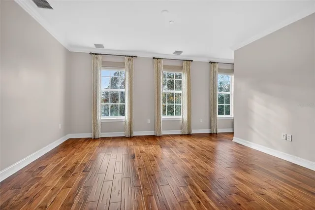 a view of an empty room with wooden floor and closet