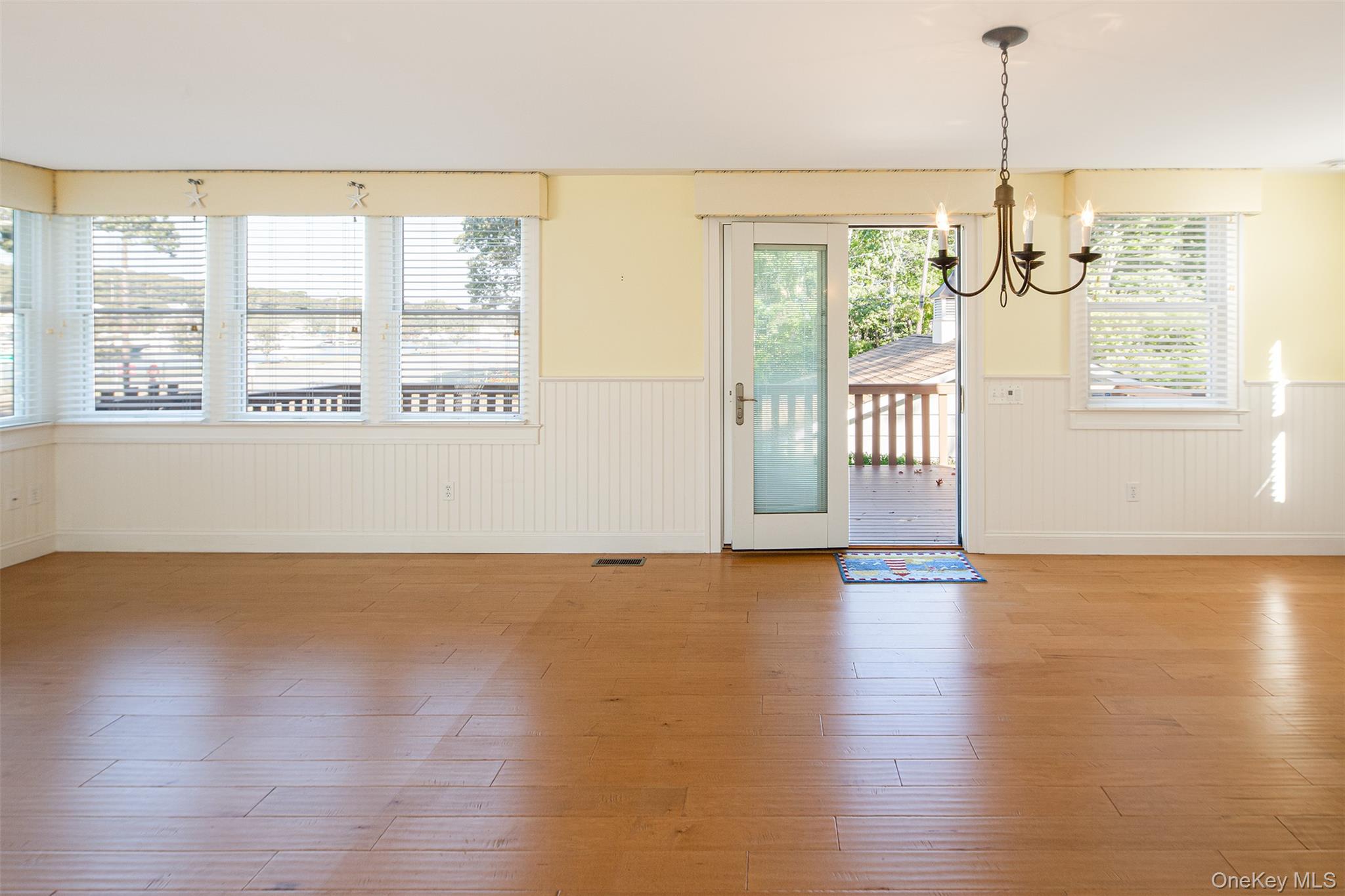 1 Canal Road Hampton Bays, NY 11946 - Photo 20 of 50 Unfurnished dining area featuring wood finished floors, a wainscoted wall, and a chandelier