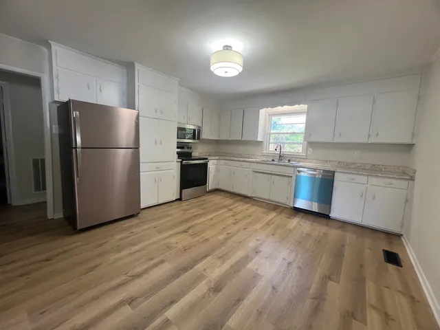 a kitchen with a refrigerator a stove top oven a sink and dishwasher with wooden floor