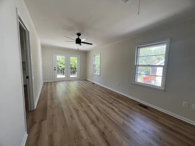 a view of an empty room with wooden floor and a window