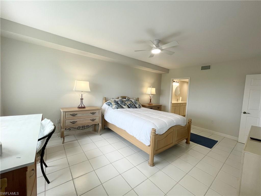 13105 Vanderbilt Drive, Unit 802 Naples, FL 34110 - Photo 11 of 32 a bedroom with a bed and a lamp on desk