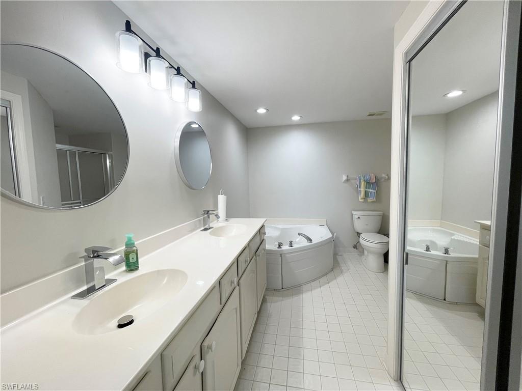 13105 Vanderbilt Drive, Unit 802 Naples, FL 34110 - Photo 16 of 32 a bathroom with a tub sink and mirror
