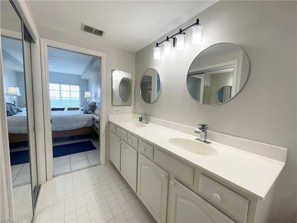 13105 Vanderbilt Drive, Unit 802 Naples, FL 34110 - Photo 19 of 32 a en suite bathroom with a double vanity sink and a mirror