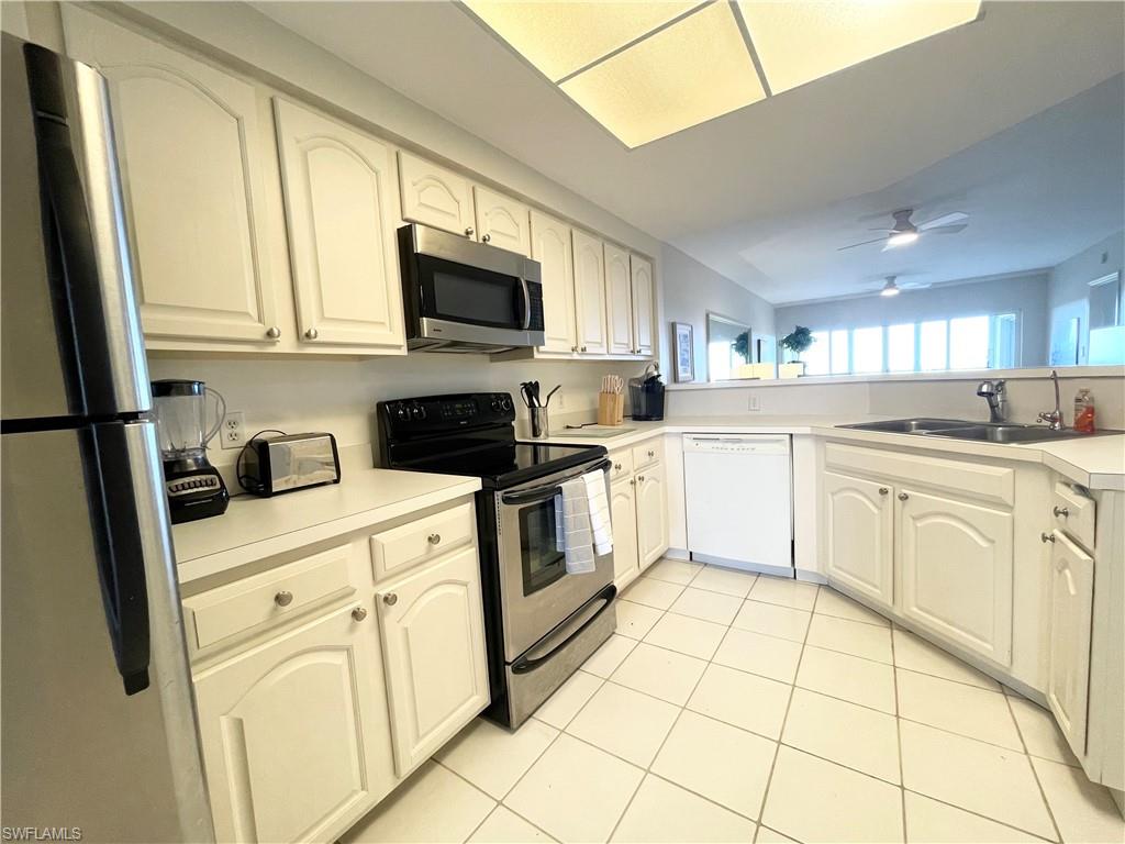 13105 Vanderbilt Drive, Unit 802 Naples, FL 34110 - Photo 7 of 32 a kitchen with white cabinets and white appliances