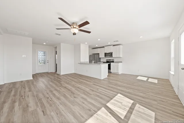 a view of kitchen and empty room with wooden floor