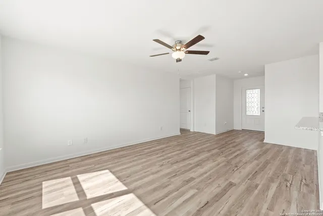 a view of empty room with wooden floor and fan