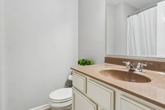 a bathroom with a granite countertop sink and a toilet