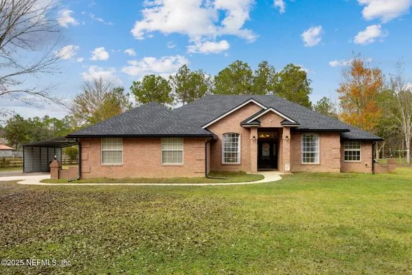 a front view of house with yard and trees in the background