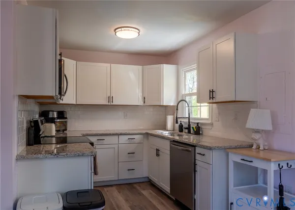 a kitchen with a sink dishwasher a stove and white cabinets