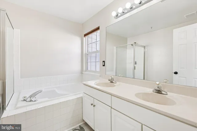 a bathroom with a sink double vanity granite tub shower and a mirror