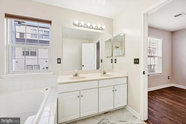 a spacious bathroom with a double vanity sink a mirror and a