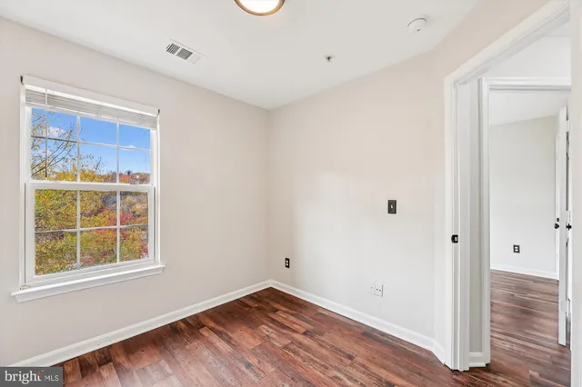 a view of an empty room with wooden floor and a window