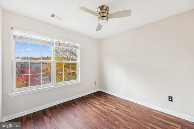 a view of empty room with wooden floor and fan