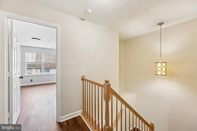 a view of a hallway with wooden floor and a bathroom
