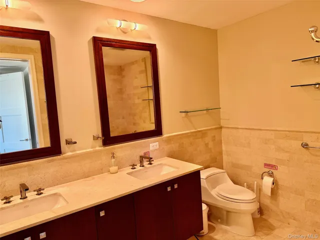 a bathroom with a double vanity sink toilet and a mirror