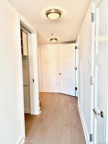 a view of a hallway with wooden floor and closet