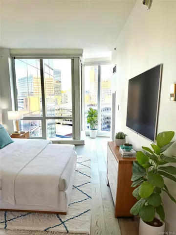 a spacious bedroom with a large window and a flat screen tv