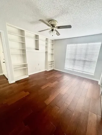 an empty room with wooden floor closet and windows