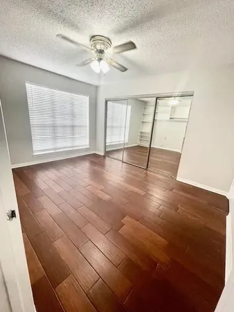an empty room with wooden floor fan and windows
