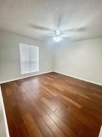 an empty room with wooden floor and fan